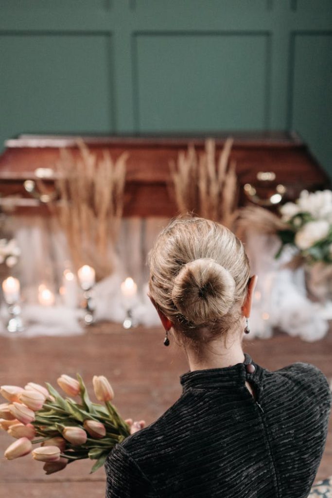 Back view of a woman holding tulips at a funeral, creating a solemn and elegant atmosphere.
